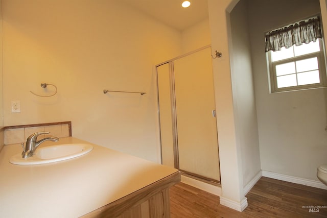 full bathroom with a stall shower, a sink, wood finished floors, toilet, and baseboards