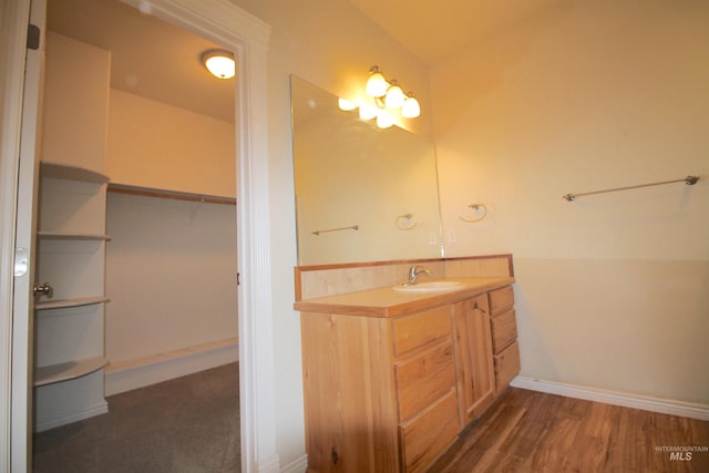 bathroom with vanity, baseboards, wood finished floors, and a spacious closet