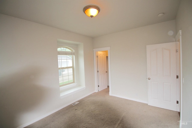 spare room featuring carpet flooring, baseboards, and a smoke detector