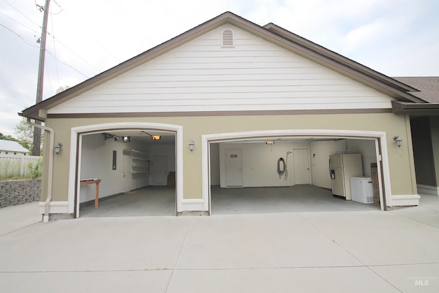 garage featuring freestanding refrigerator and concrete driveway