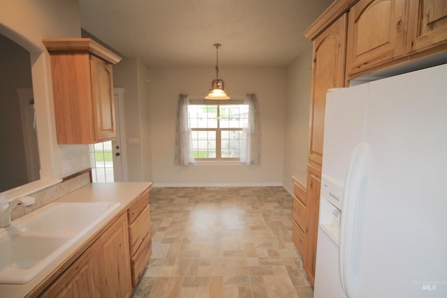 kitchen with white fridge with ice dispenser, a sink, pendant lighting, light countertops, and stone finish floors