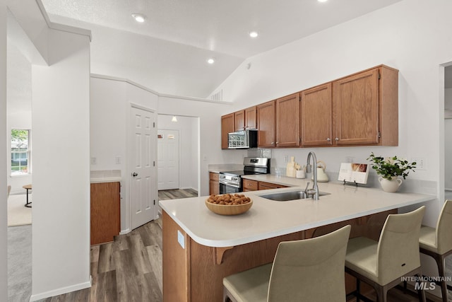 8520 W Willowcourt Dr, Boise, ID 83714 - kitchen with stainless steel appliances, a sink, light countertops, wood finished floors, and vaulted ceiling