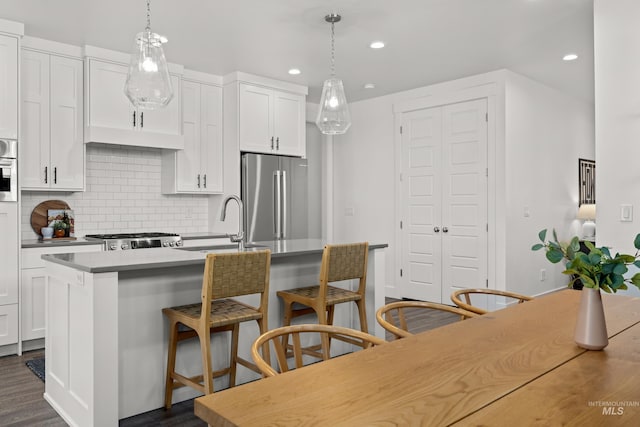 10148 Irongate Dr, Nampa, ID 83687 - kitchen featuring a kitchen island with sink, a sink, tasteful backsplash, pendant lighting, and appliances with stainless steel finishes