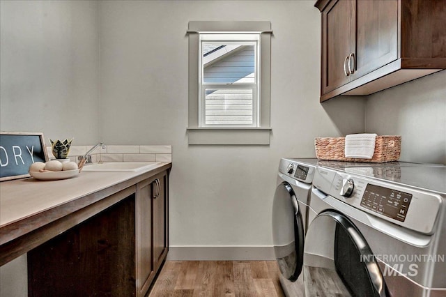 2128 N Woodcreek St, Boise, ID 83704 - washroom featuring cabinet space, independent washer and dryer, light wood-style flooring, and baseboards