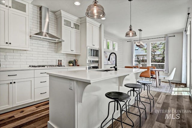 2128 N Woodcreek St, Boise, ID 83704 - kitchen with wall chimney exhaust hood, a sink, appliances with stainless steel finishes, dark wood finished floors, and light countertops