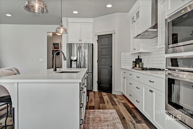 2128 N Woodcreek St, Boise, ID 83704 - kitchen featuring appliances with stainless steel finishes, wall chimney range hood, a sink, a kitchen bar, and light countertops