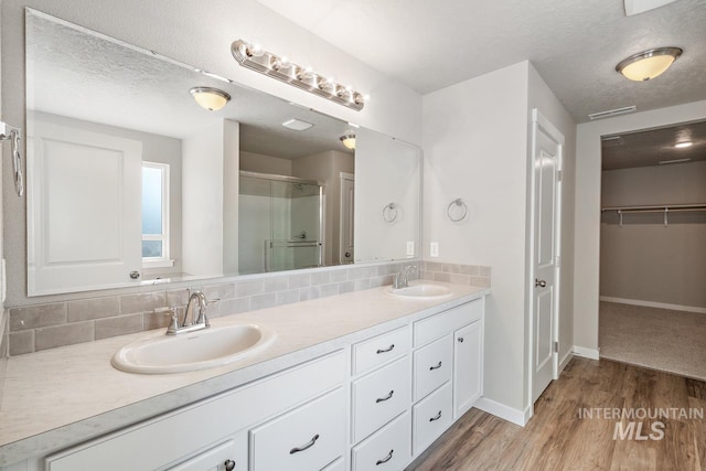 bathroom featuring backsplash, wood-type flooring, and a textured ceiling