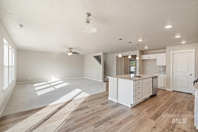 kitchen with ceiling fan, sink, an island with sink, decorative light fixtures, and white cabinets