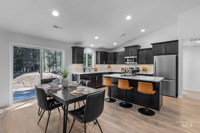 kitchen featuring lofted ceiling, a sink, visible vents, light countertops, and appliances with stainless steel finishes