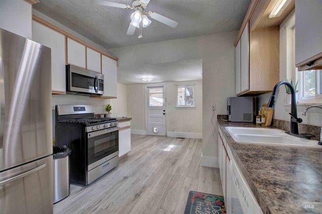 412 6th Ave N, Twin Falls, ID 83301 - kitchen featuring stainless steel appliances, light wood-style flooring, ceiling fan, white cabinetry, and dark countertops