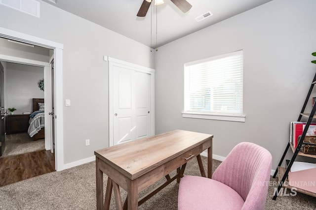 carpeted office with baseboards, visible vents, and ceiling fan