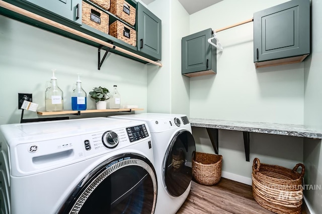 laundry area with cabinet space, washer and dryer, and wood finished floors