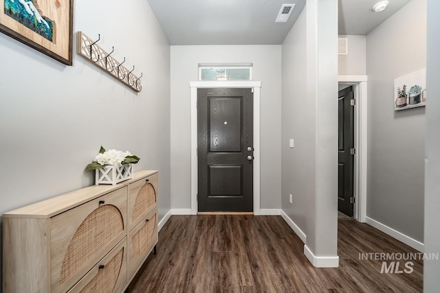 foyer entrance with baseboards, visible vents, and dark wood finished floors