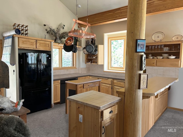 kitchen with a wealth of natural light, black appliances, light colored carpet, and a kitchen island