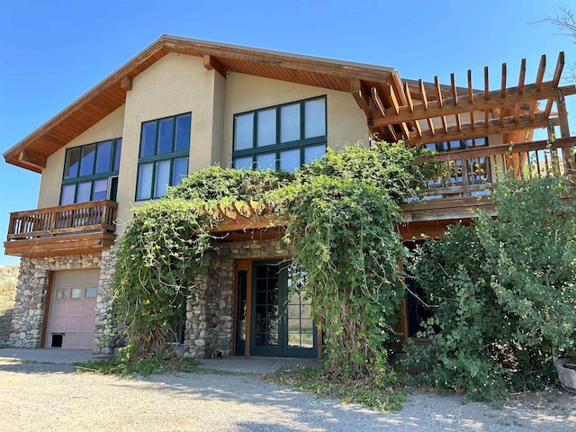 1262 N Soldier Creek Rd, Fairfield, ID 83327 - view of front facade with a balcony, stone siding, an attached garage, stucco siding, and french doors