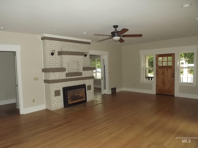 unfurnished living room featuring hardwood / wood-style floors, a large fireplace, and ceiling fan