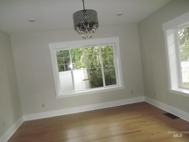 unfurnished dining area with a chandelier and hardwood / wood-style floors