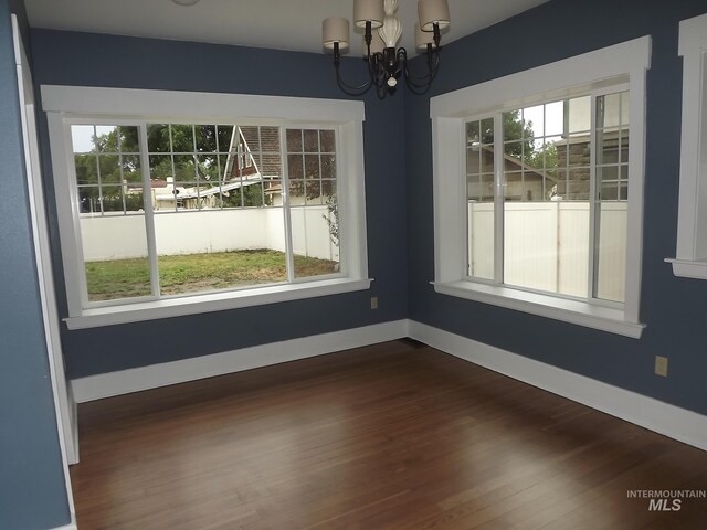 empty room featuring a chandelier and hardwood / wood-style flooring