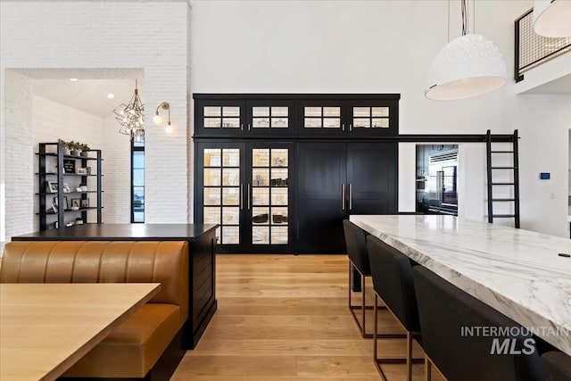 kitchen featuring brick wall, a high ceiling, light hardwood / wood-style flooring, and decorative light fixtures