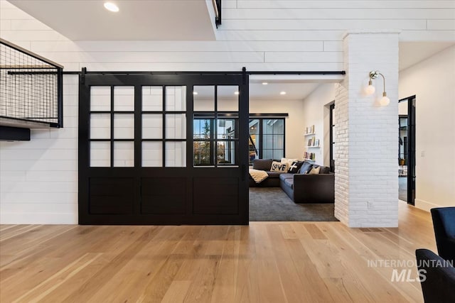 entrance foyer featuring hardwood / wood-style floors, a barn door, and decorative columns