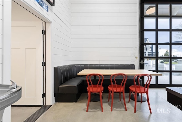 dining room with wood walls and concrete flooring