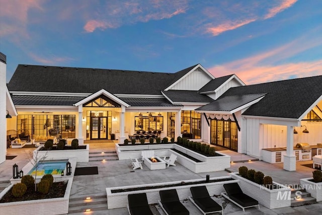 back house at dusk featuring a patio, french doors, and an outdoor living space