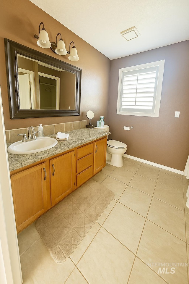 bathroom with tile patterned floors, baseboards, vanity, and toilet