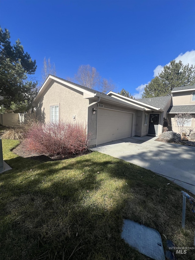 view of front of home with a garage, driveway, a front lawn, and stucco siding