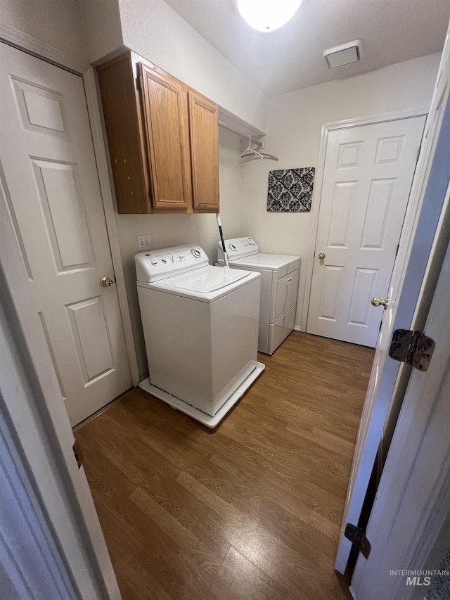 washroom featuring cabinet space, wood finished floors, and washer and dryer