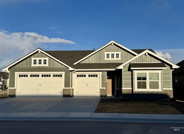craftsman house featuring stone siding, a garage, concrete driveway, and roof with shingles
