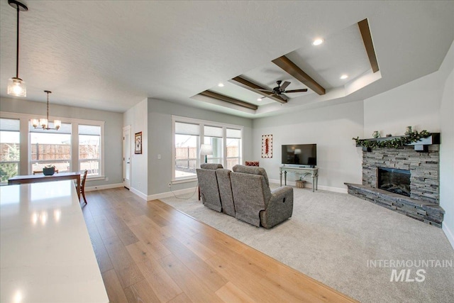 living area featuring wood finished floors, a stone fireplace, baseboards, ceiling fan with notable chandelier, and recessed lighting