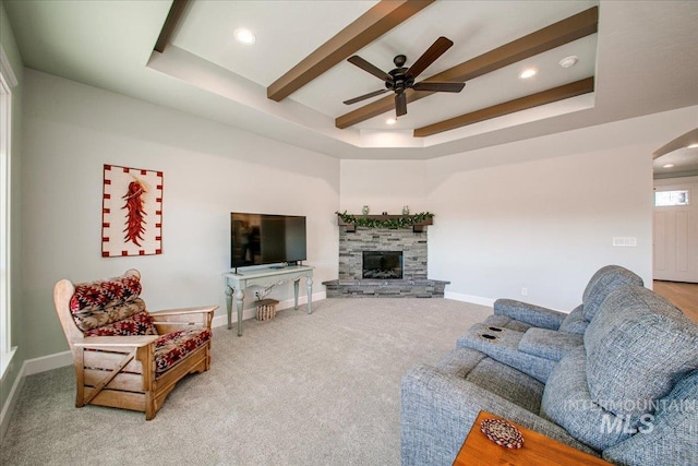 living area featuring baseboards, beamed ceiling, arched walkways, and a ceiling fan