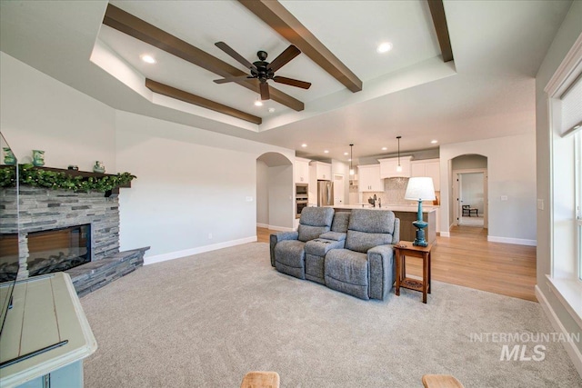living area with arched walkways, ceiling fan, and a raised ceiling