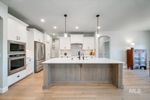 kitchen featuring backsplash, light countertops, appliances with stainless steel finishes, and white cabinets