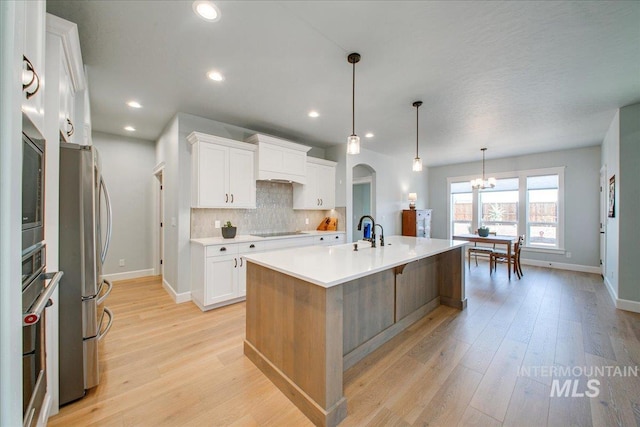kitchen featuring freestanding refrigerator, light wood-style flooring, backsplash, and black electric stovetop