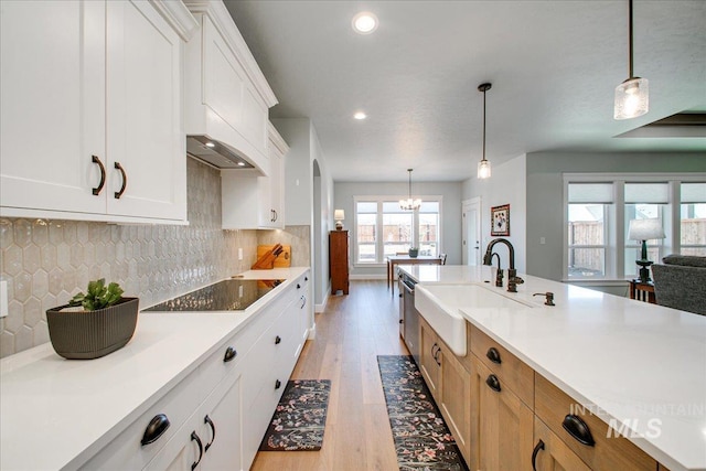 kitchen featuring black electric cooktop, light countertops, a sink, and a chandelier
