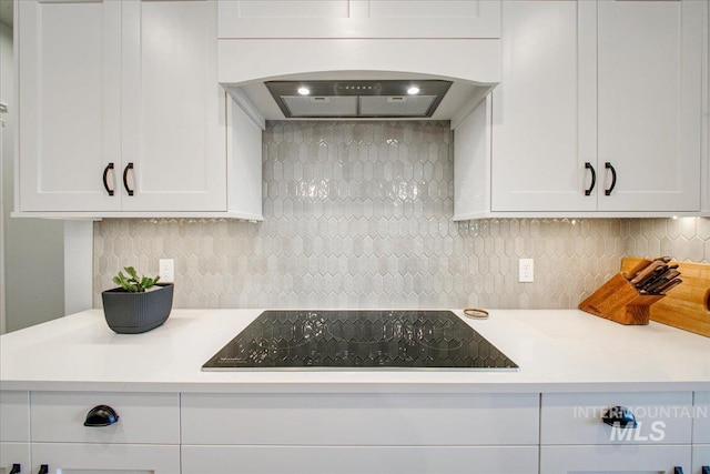kitchen featuring white cabinetry, black electric cooktop, light countertops, and premium range hood