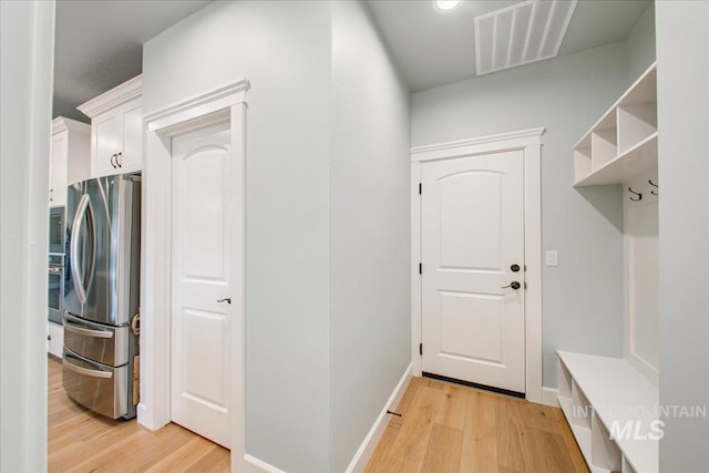 mudroom with baseboards, light wood finished floors, and visible vents