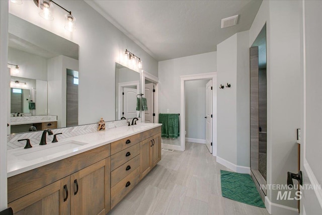 bathroom with double vanity, a sink, baseboards, and visible vents