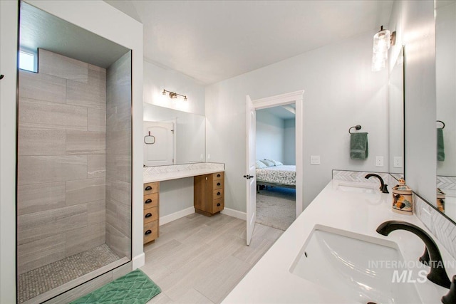 ensuite bathroom with connected bathroom, double vanity, a tile shower, and a sink