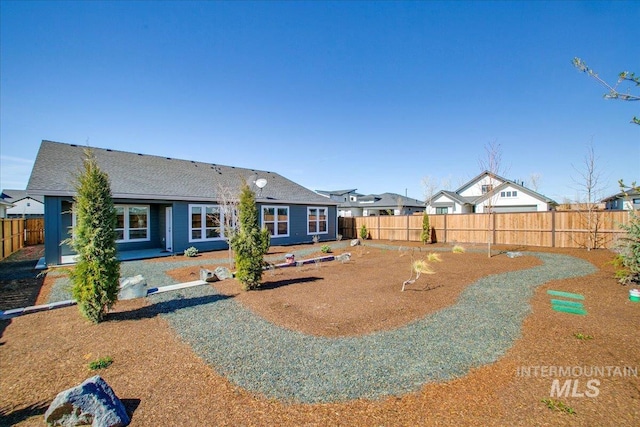 rear view of property with a fenced backyard, a residential view, and a shingled roof