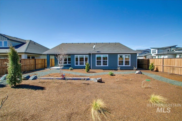 rear view of house featuring a fenced backyard