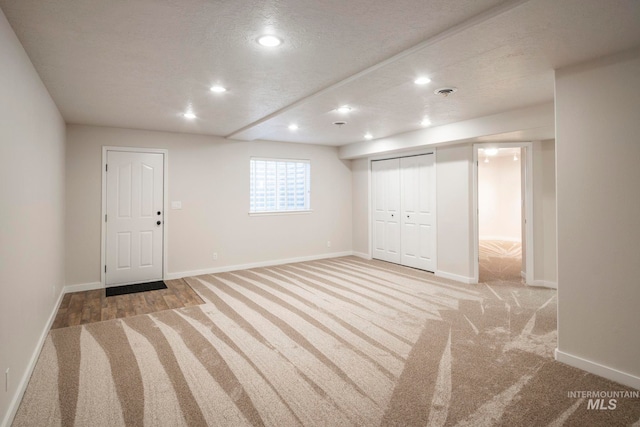 basement featuring a textured ceiling and light colored carpet