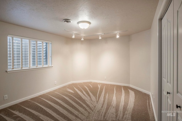 spare room featuring carpet flooring, a textured ceiling, and rail lighting