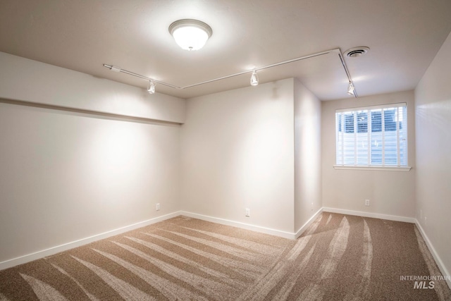 spare room featuring carpet and track lighting