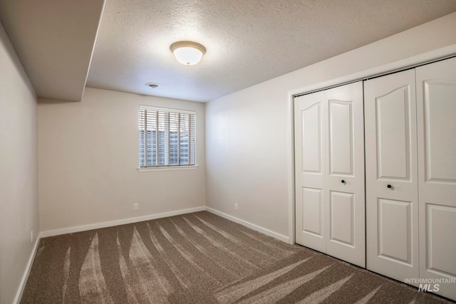 unfurnished bedroom featuring a closet, carpet, and a textured ceiling