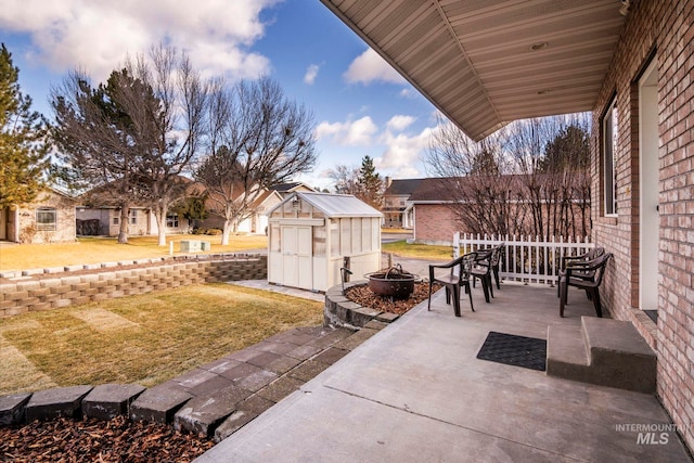 patio terrace at dusk with a lawn, a storage shed, and an outdoor fire pit