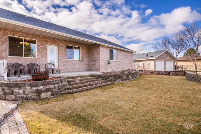 rear view of property with a patio area, a garage, a yard, and an outdoor fire pit