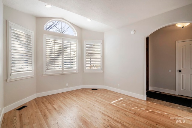 unfurnished room with light hardwood / wood-style floors, lofted ceiling, and a textured ceiling