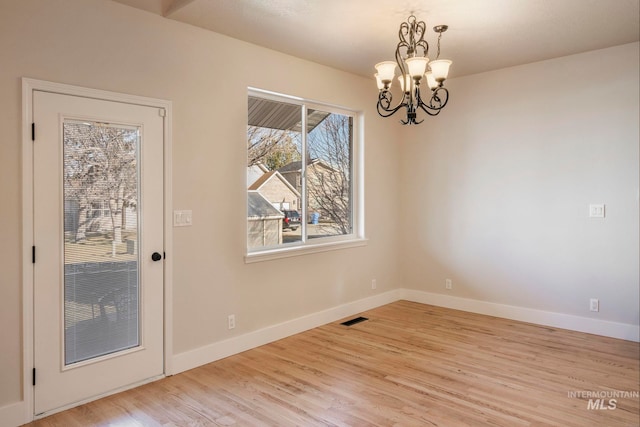 unfurnished dining area with light wood-type flooring and a notable chandelier